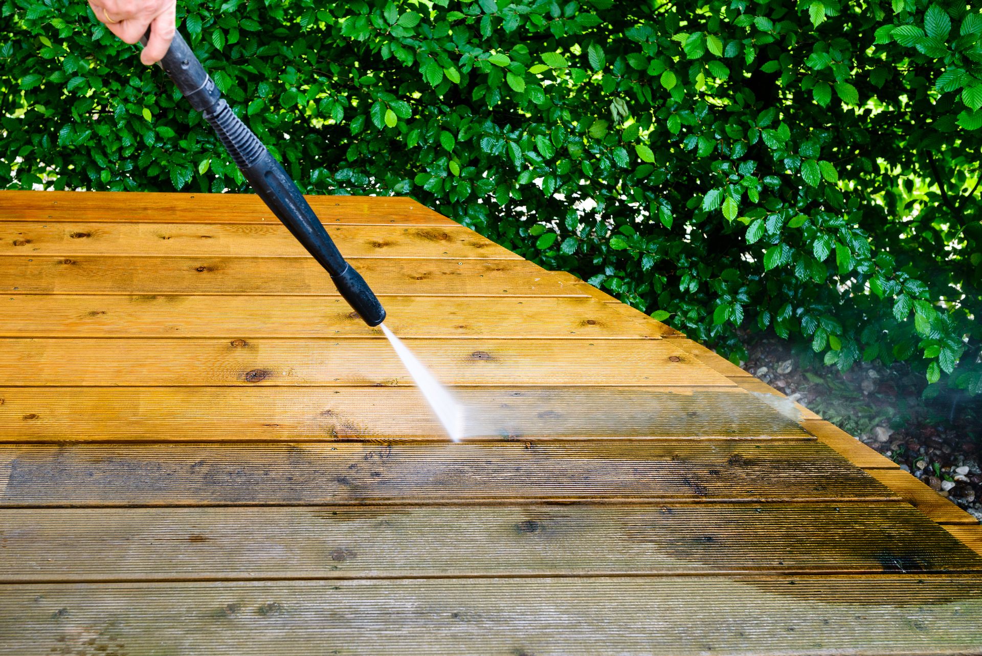 Power washing a wooden deck, removing dirt and grime.