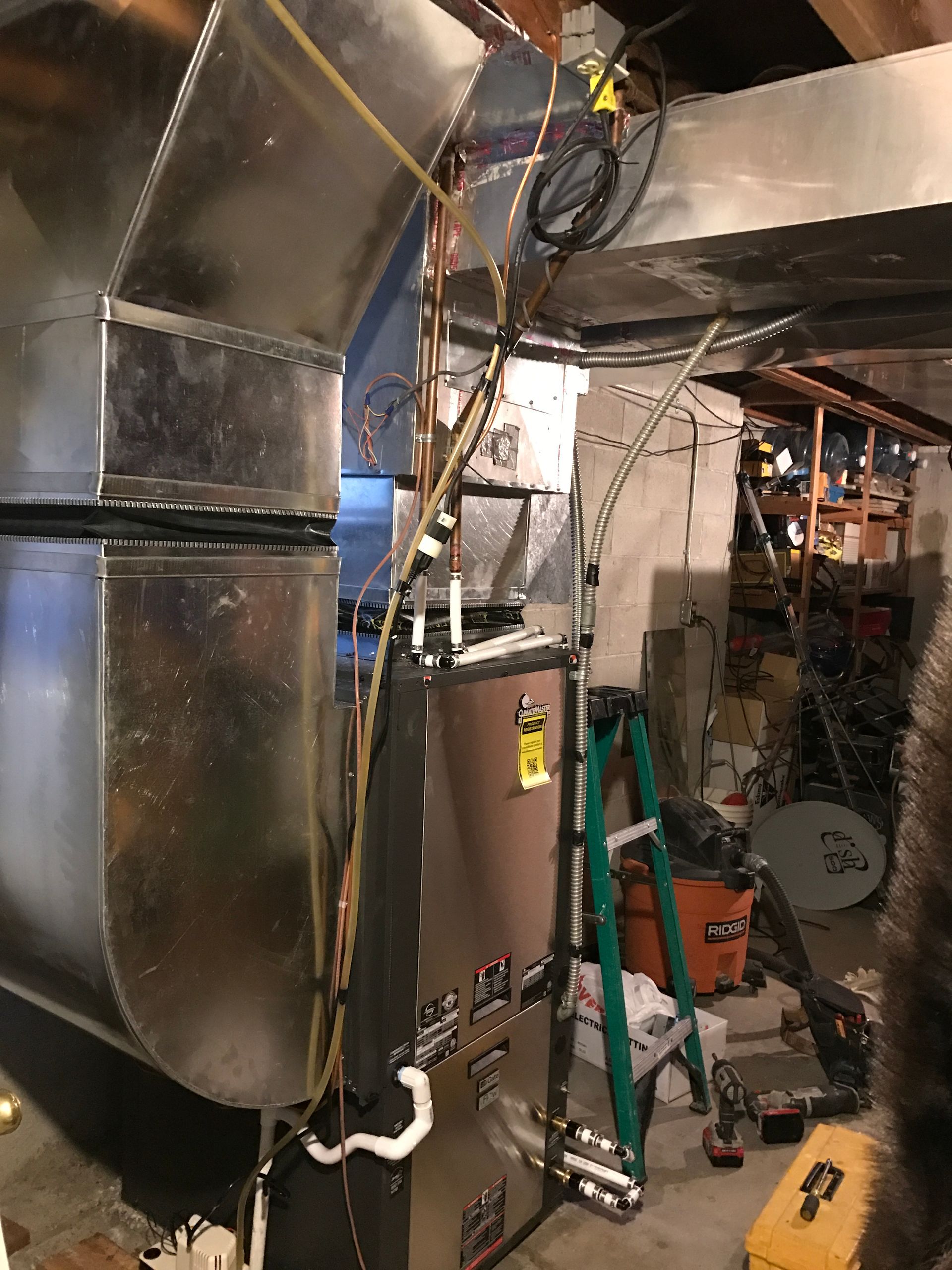 A raccoon is standing next to a furnace in a basement.