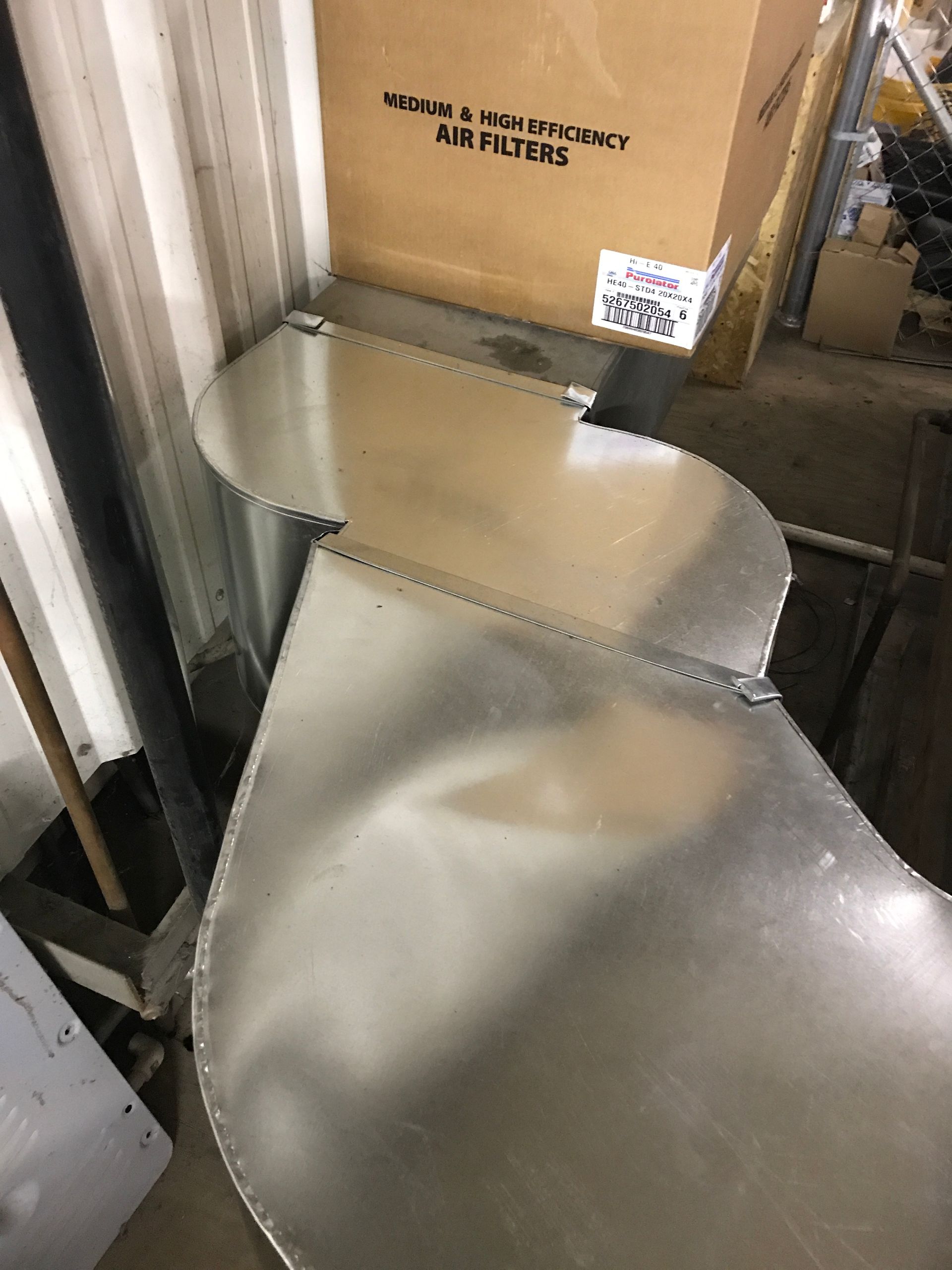 A metal pipe is sitting next to a cardboard box in a room.