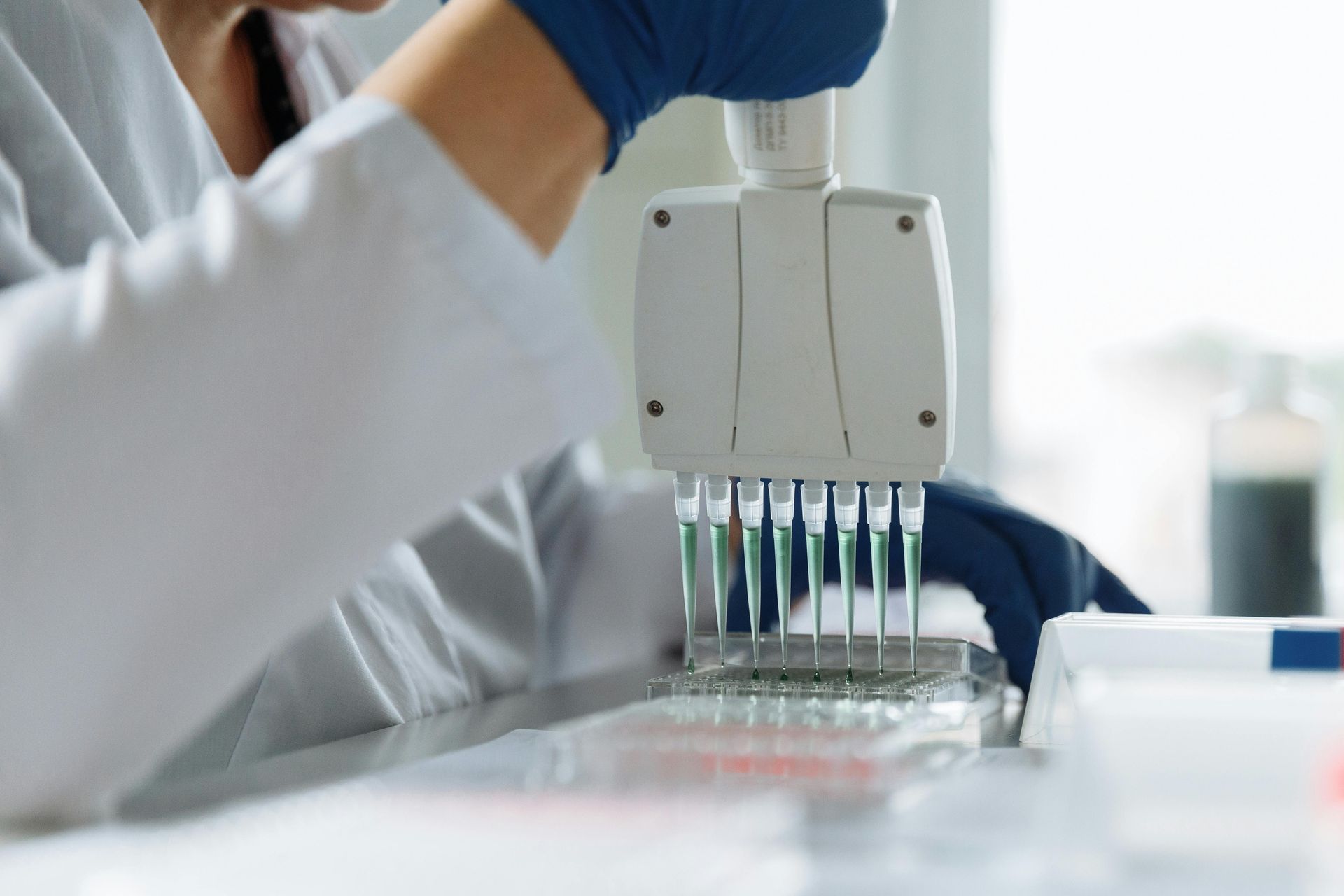 Lab technician using a pipette dispenser in a bright laboratory