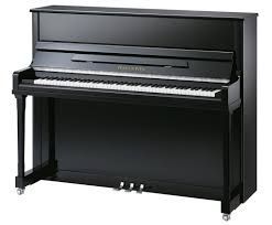 A black upright piano is sitting on a white surface.