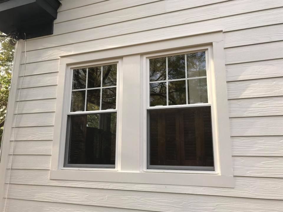 A white-framed, double-hung window with a six-pane grid on the upper sashes, set into horizontal white wood siding.