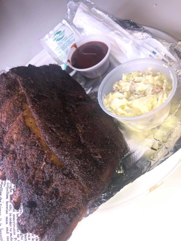 Tray with a dark roast chicken, gravy, and mashed potatoes in a takeout container