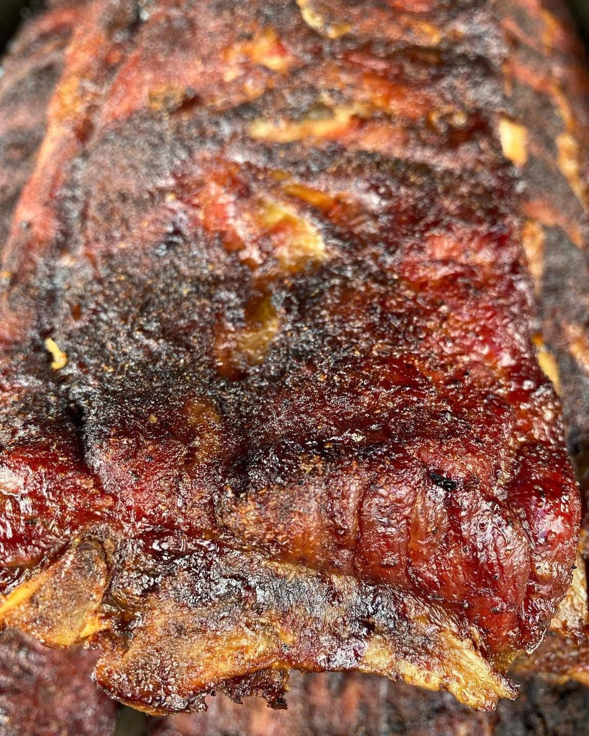 Close-up of glazed, charred grilled meat with a dark reddish-brown crust
