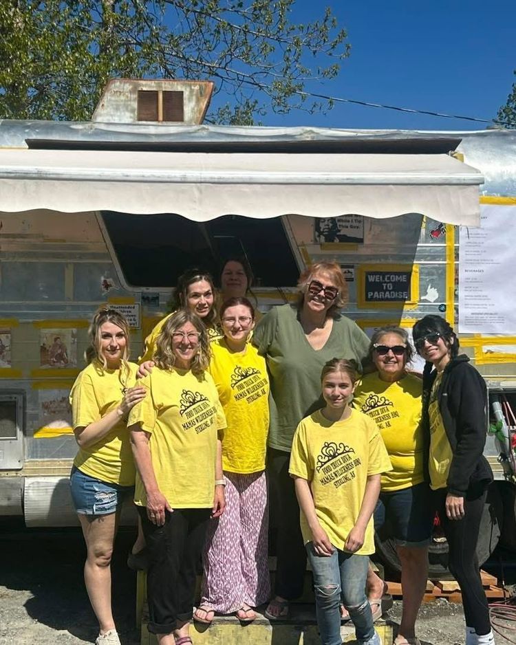 Group of people in yellow T-shirts posing in front of a food truck outdoors.