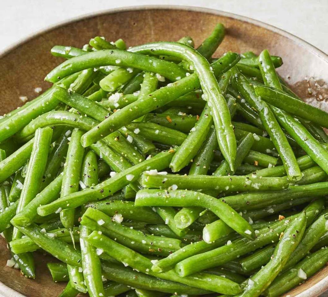 Close-up of seasoned green beans in a shallow bowl