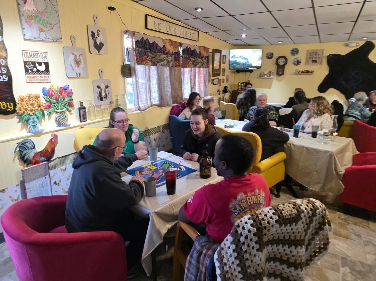 People seated in a cozy cafe, chatting at tables with colorful walls and decor.