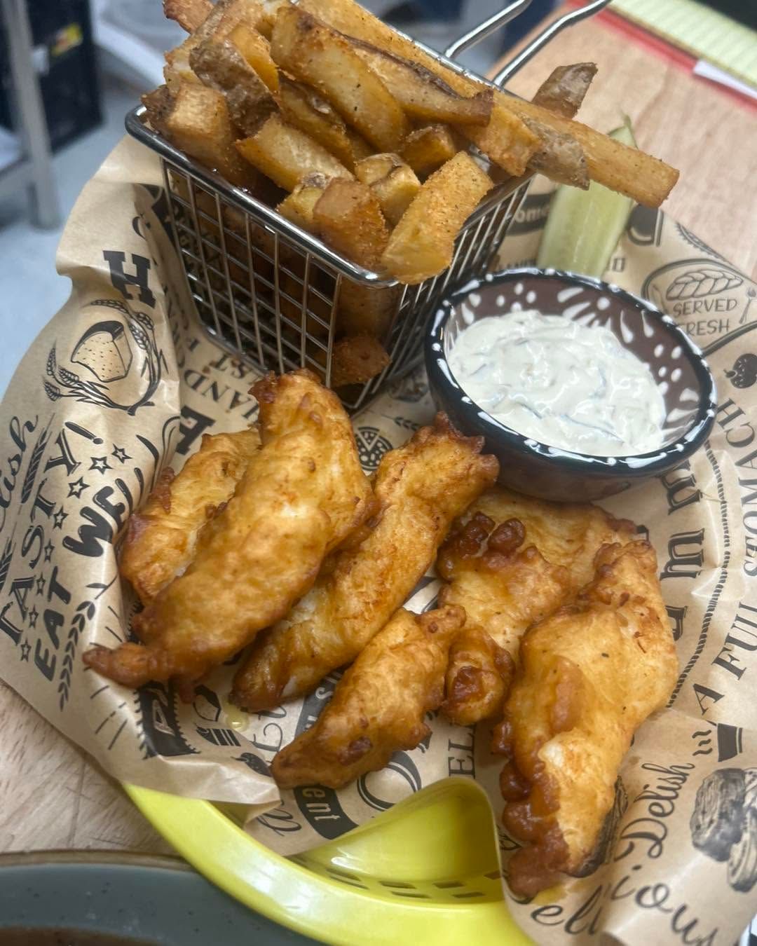 Plate of fried fish and fries with tartar sauce on a restaurant tray.
