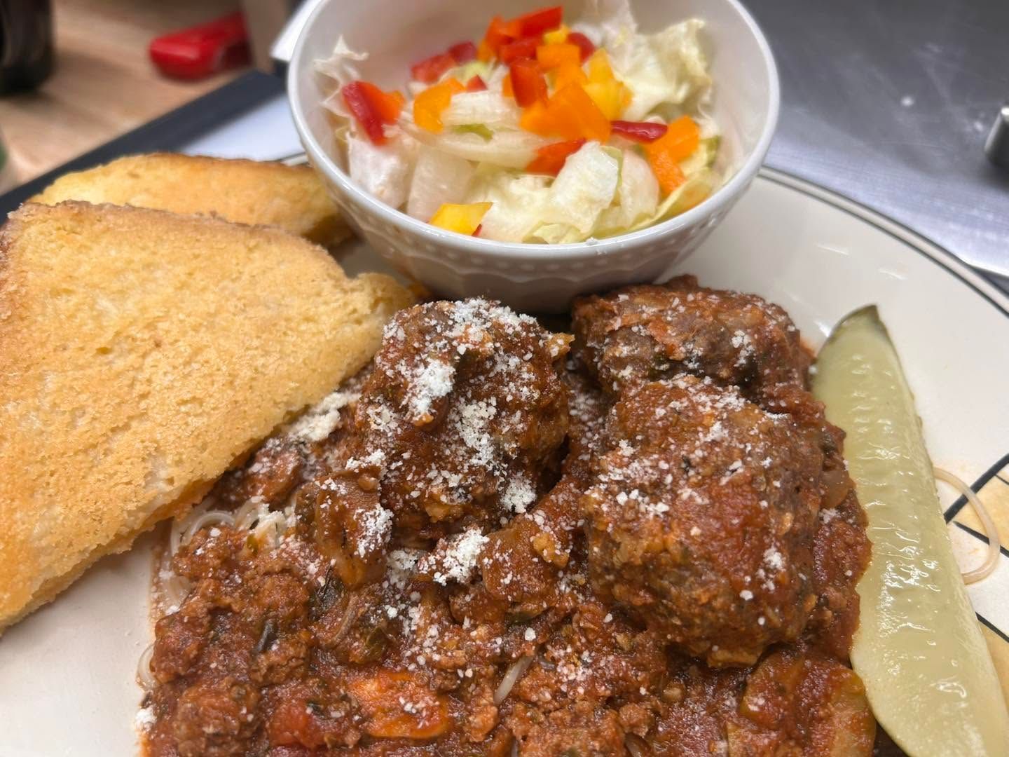 Plated fried chicken with bread, pickle, and coleslaw on a table