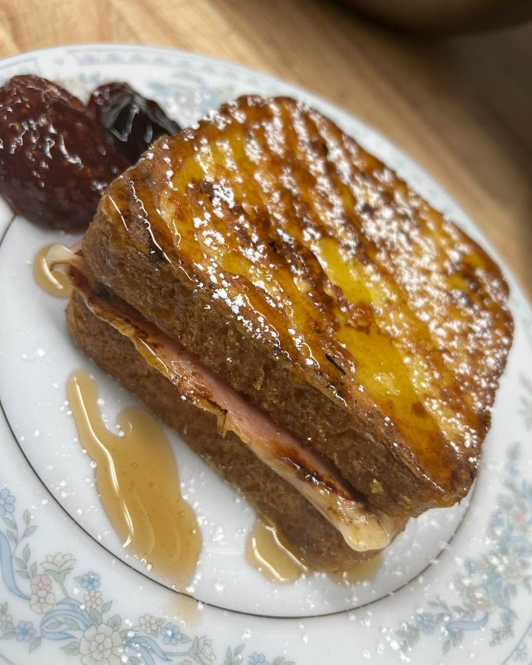 French toast topped with syrup on a floral plate, with jam on the side