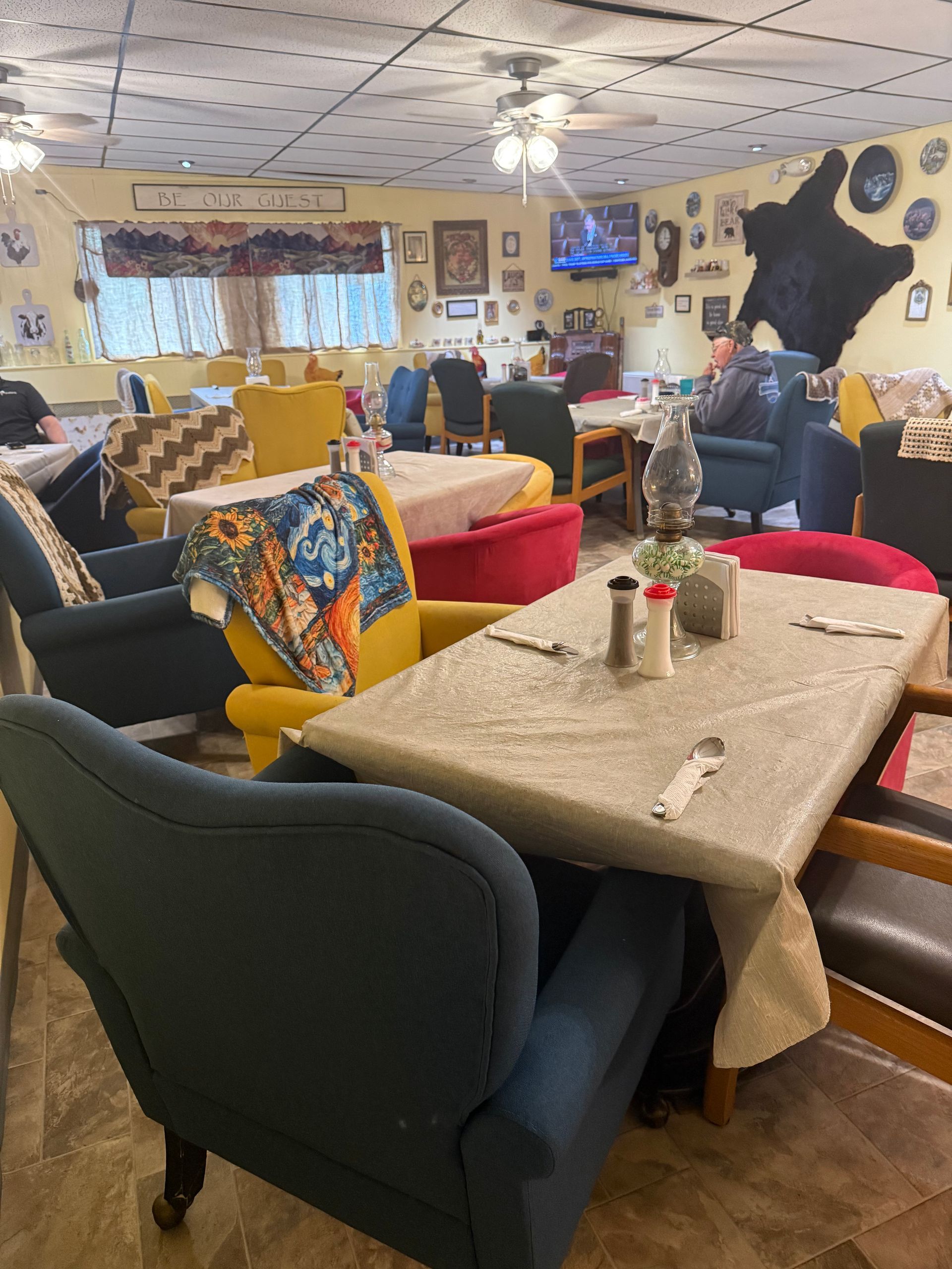 Cozy café lounge with upholstered chairs, tables, and wall art in warm lighting