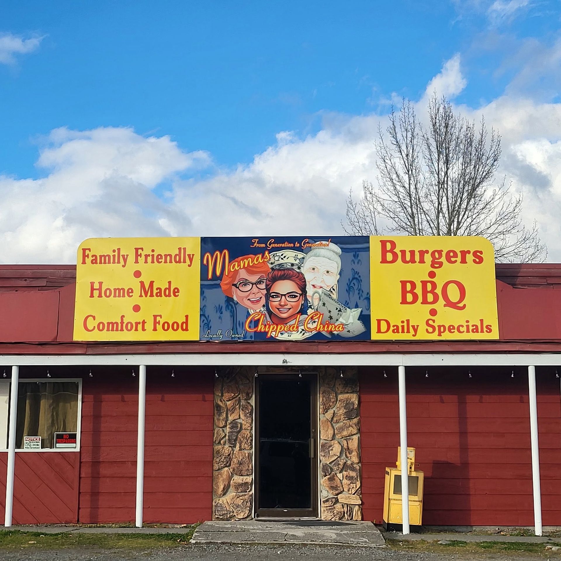 Red roadside diner with yellow signs reading “Family Friendly Home Made Comfort Food” and “Burgers BBQ Daily Specials.”