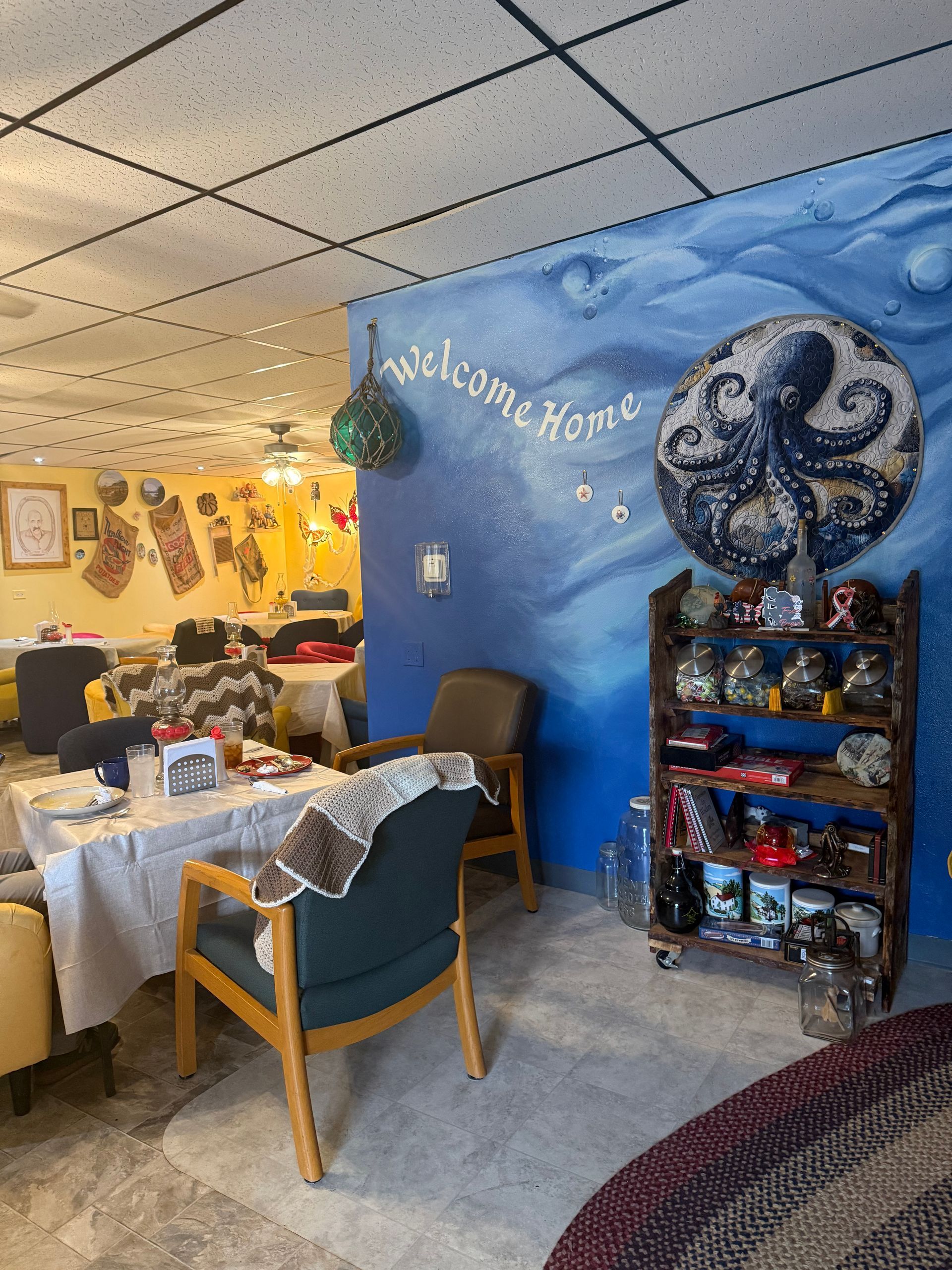 Cozy café seating area with blue accent wall, holiday decorations, and a small display shelf with snacks