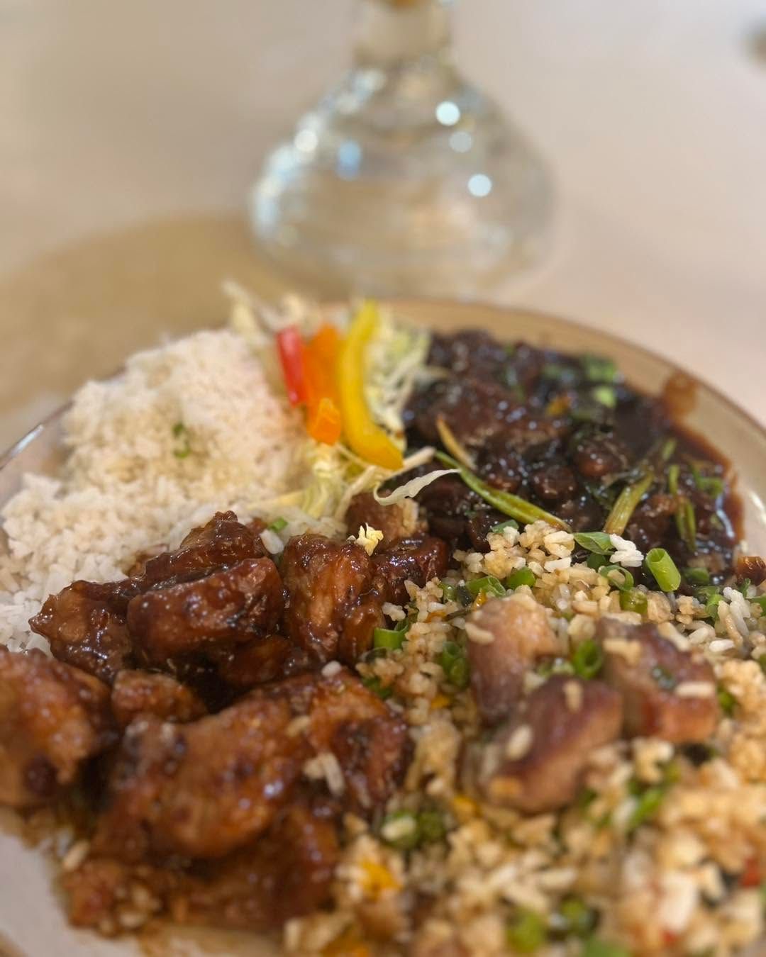 Plate of rice with saucy meat, vegetables, and garnishes on a table