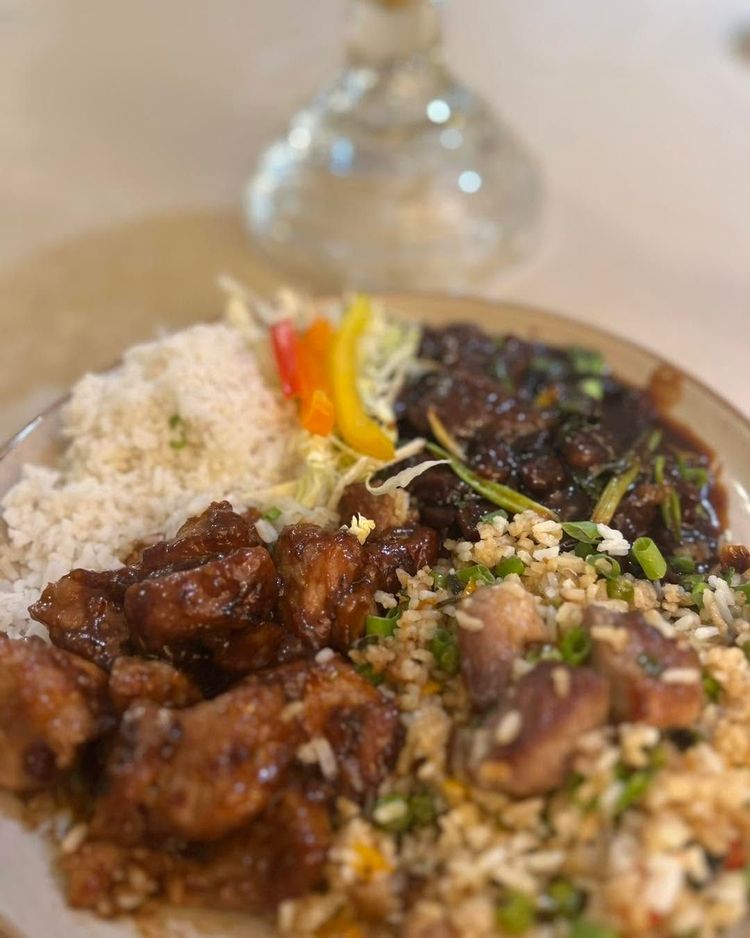 Plated meal with rice, glazed meat, vegetables, and a glass in the background