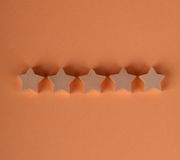 Five beige star-shaped cookies lined up on an orange background.