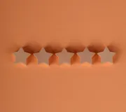 Five beige star-shaped cookies lined up on an orange background.
