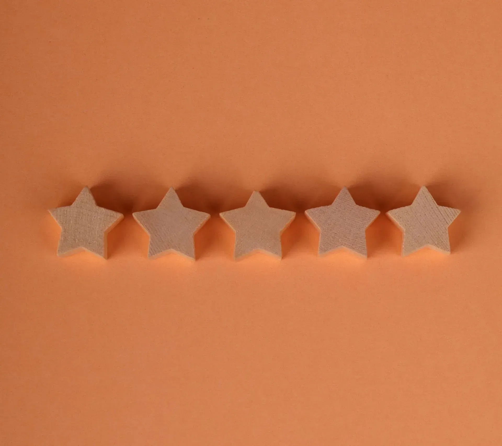 Five beige star-shaped cookies lined up on an orange background.