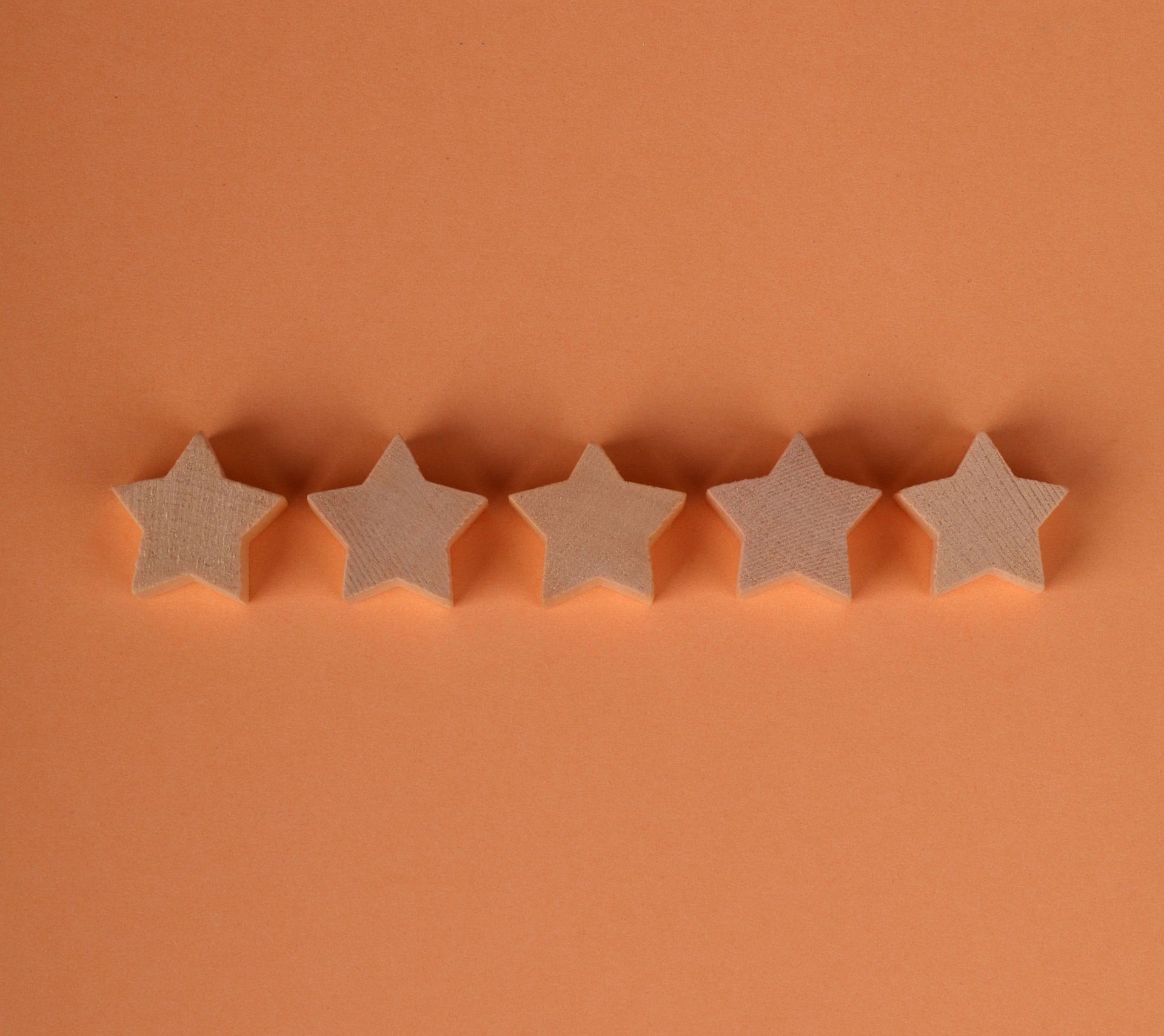 Five beige star-shaped cookies lined up on an orange background.
