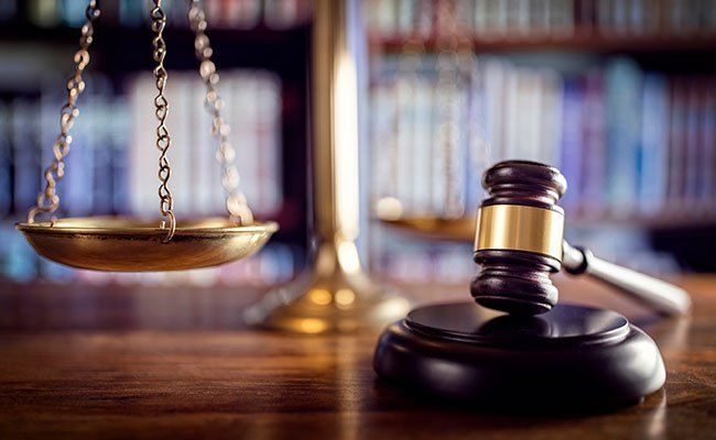 scale next to a gavel with bookshelf in  the background