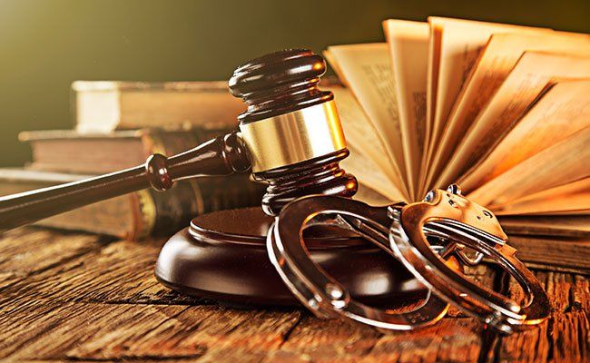 gavel next to handcuffs with books in background