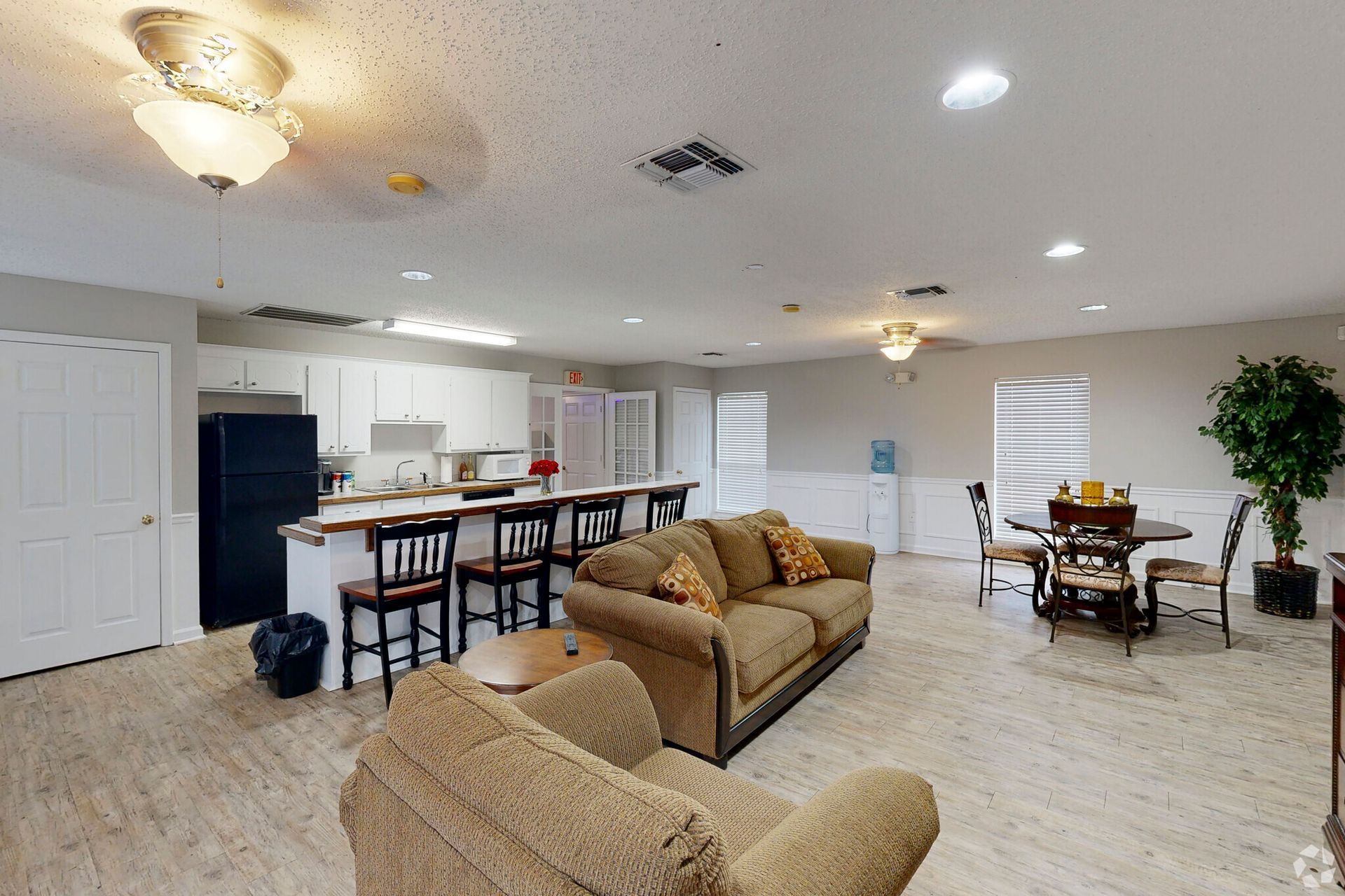 Photo of a large open living room area with a kitchen in the background and a kitchen island