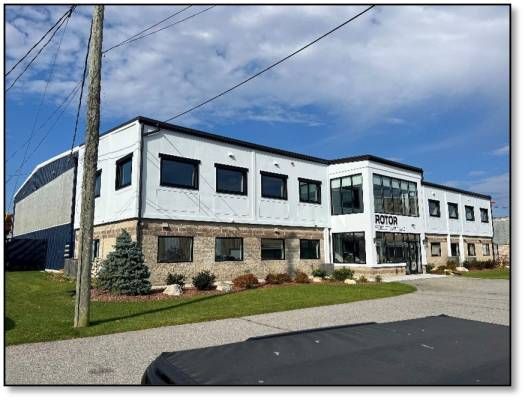 Modern white and gray two-story building with black-framed windows, brick base, and arched structure on left.