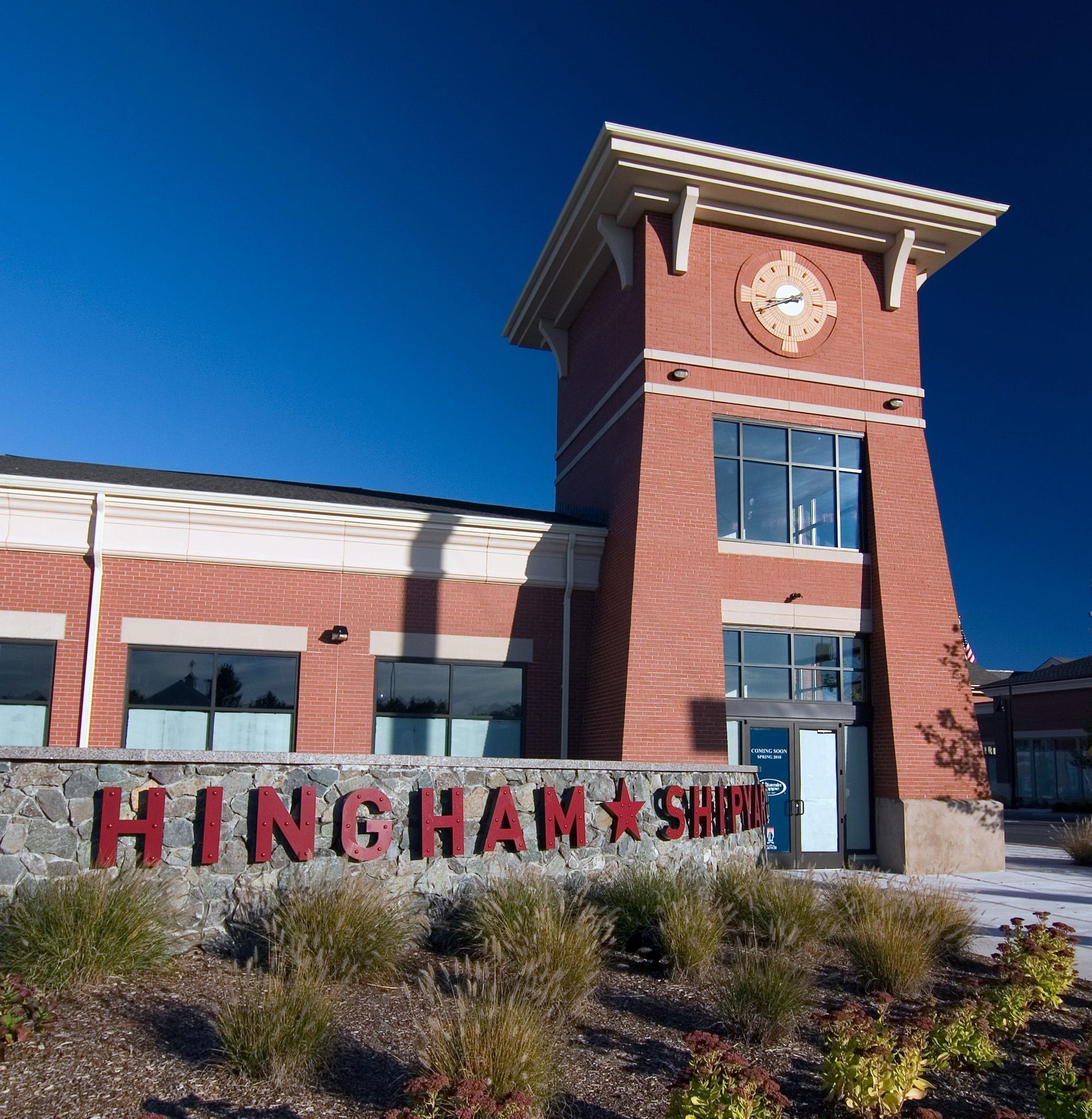 A red brick building with a clock tower and a stone sign that reads
