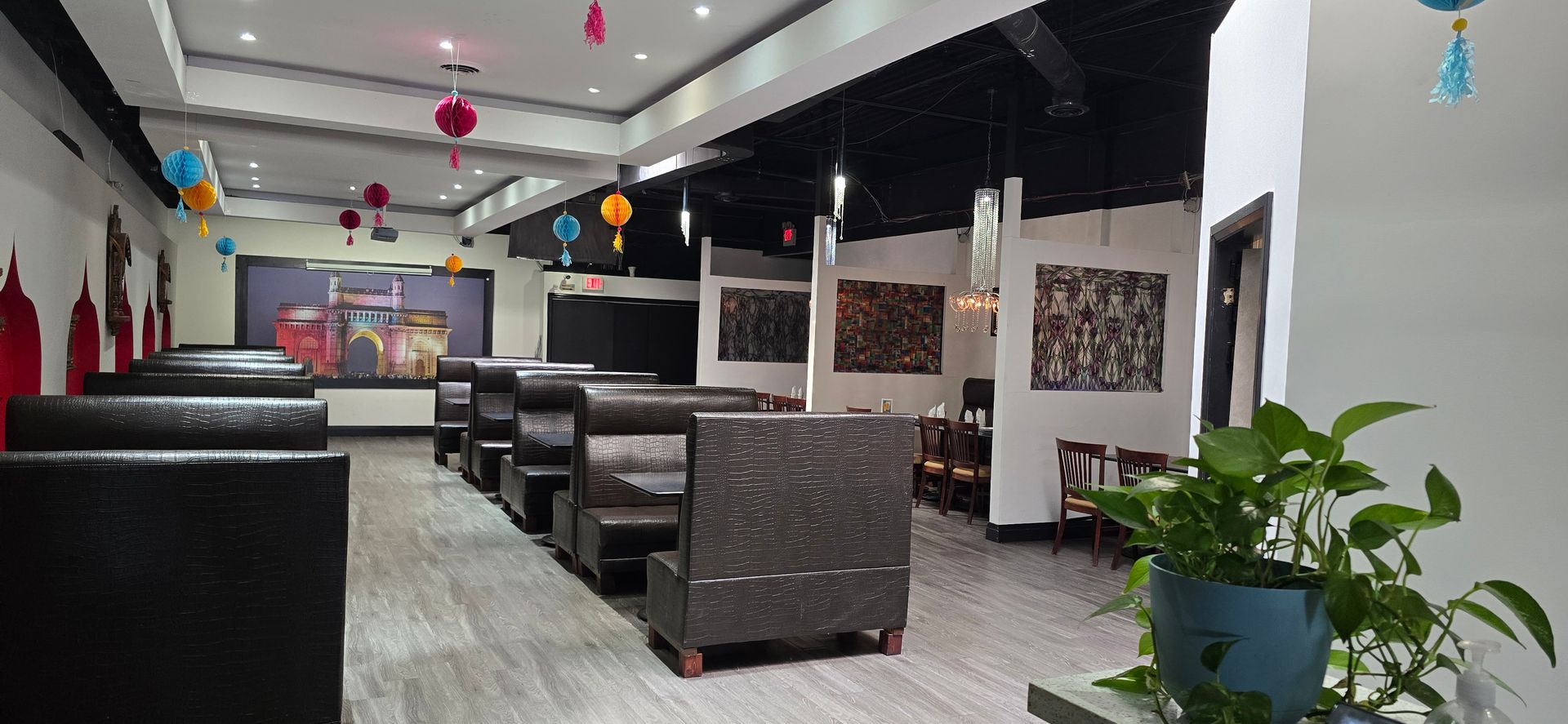 A restaurant with a lot of tables and chairs and a plant in the middle of the room.