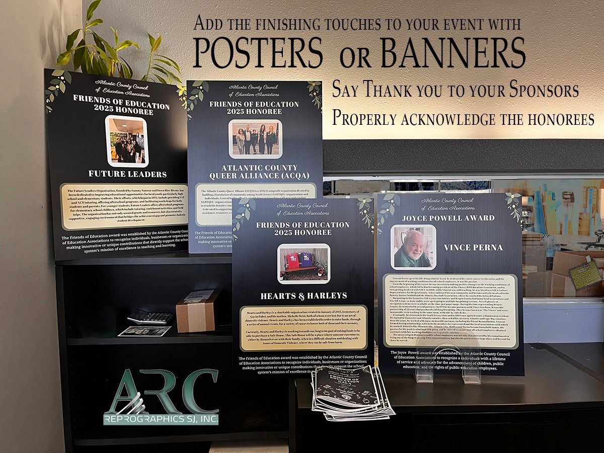 Posters and banners on a table display honoring sponsors, with black and beige signs in a room