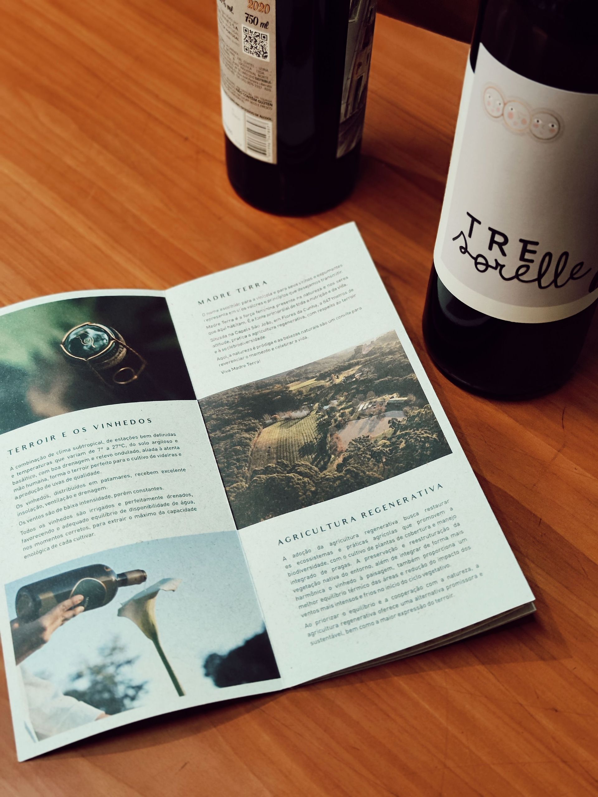 Open magazine on a wooden table beside wine bottles and glasses.