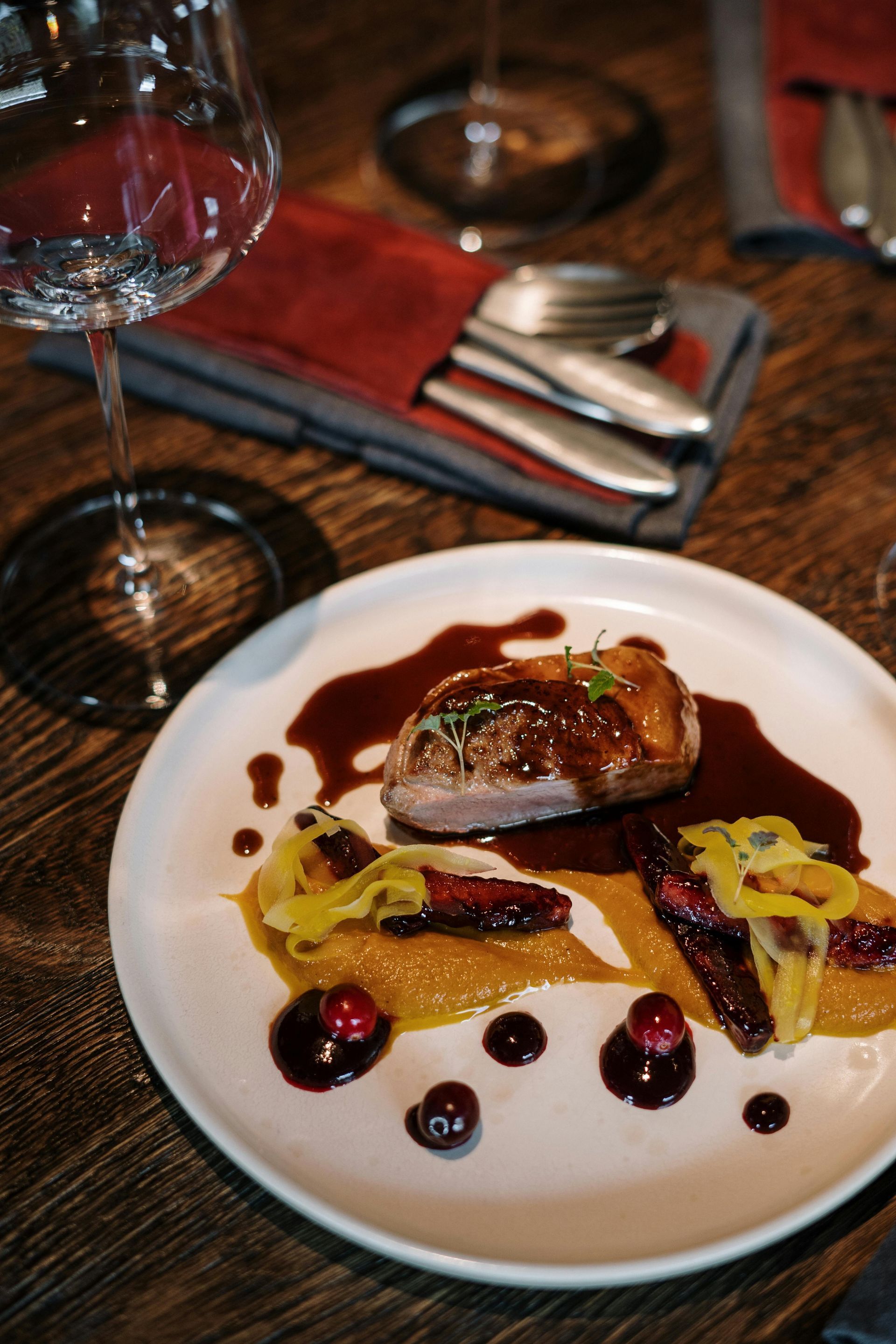 Plated gourmet dish with seared meat, vegetables, and sauce on a restaurant table