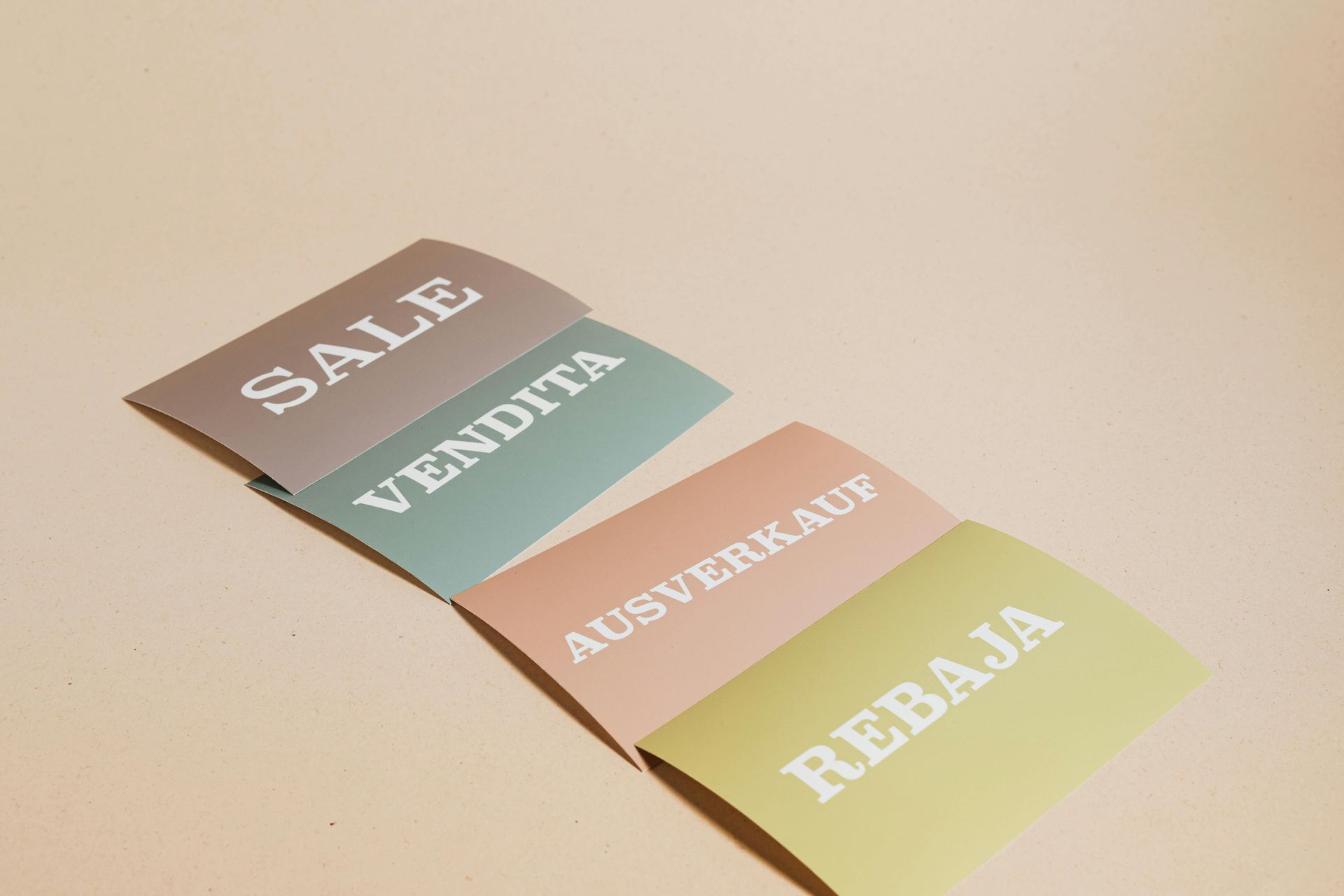 Four colorful sale signs reading “SALE,” “VENDITA,” “AUSVERKAUF,” and “REBAJA” arranged diagonally