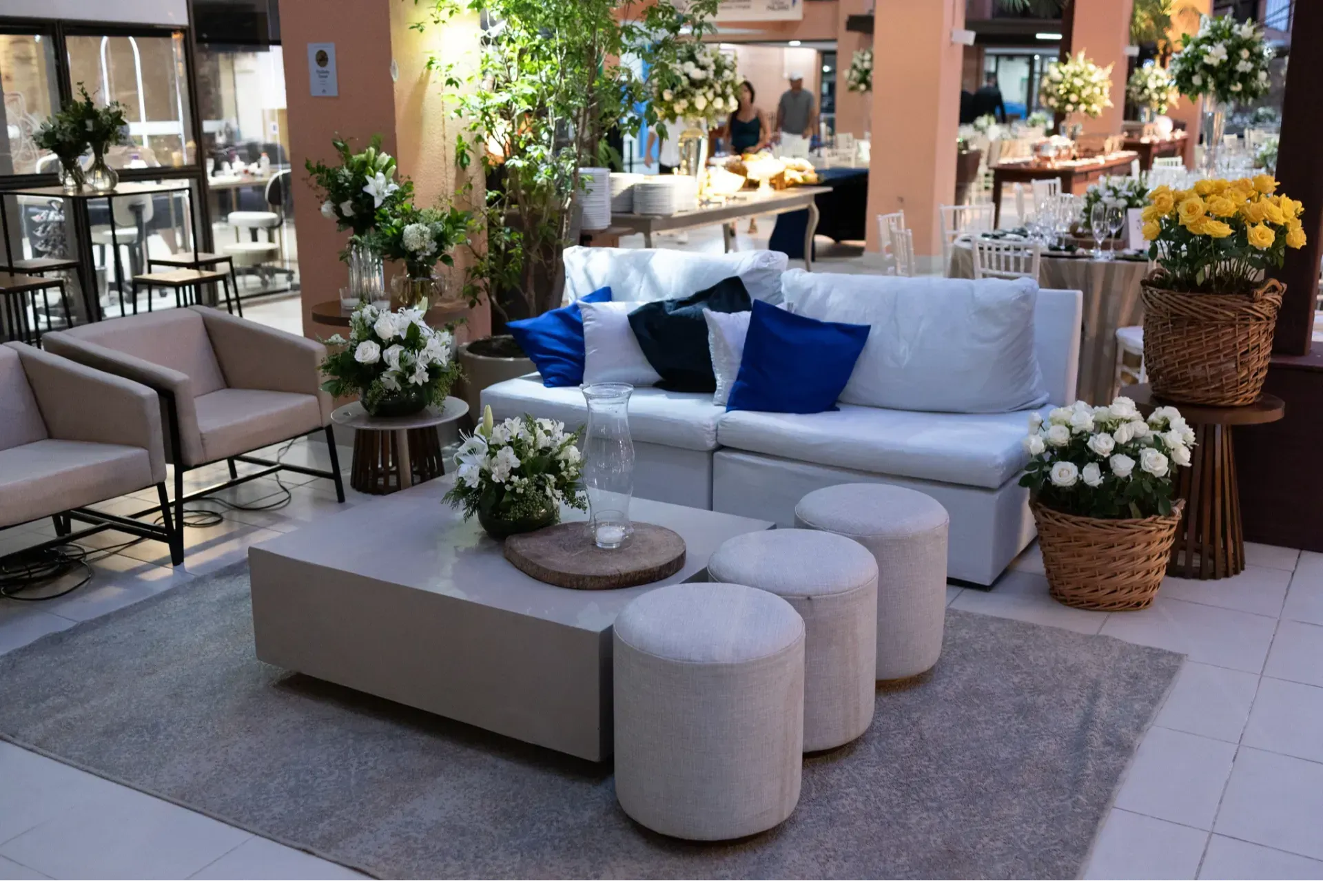 Sala de estar moderna em tons de branco e azul, com sofás, cadeiras, flores e decoração em exposição em um showroom.