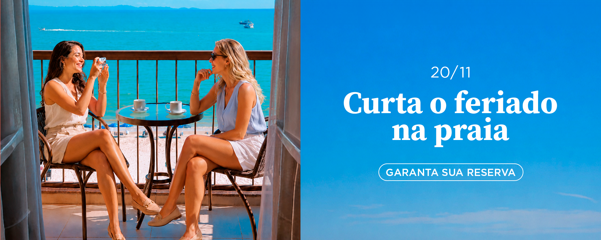 Duas pessoas brindam numa varanda à beira-mar; o texto diz: “Aproveite o feriado na praia”.