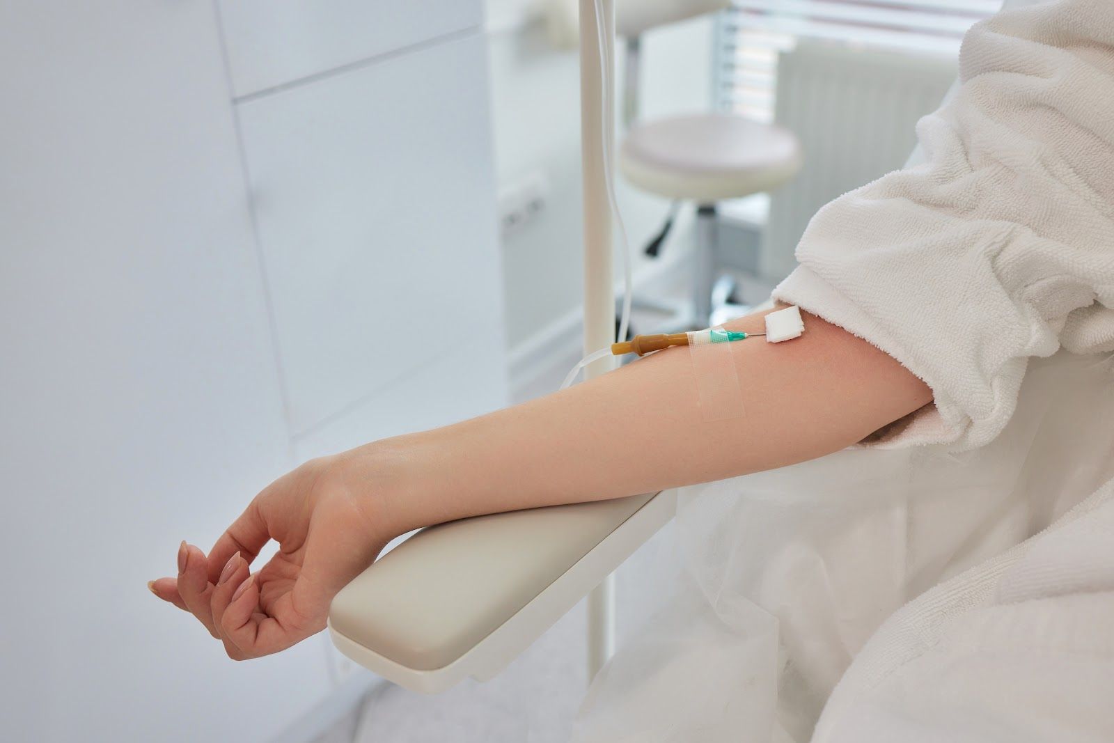 Arm resting on a padded clinic chair, with an IV catheter taped near the wrist.