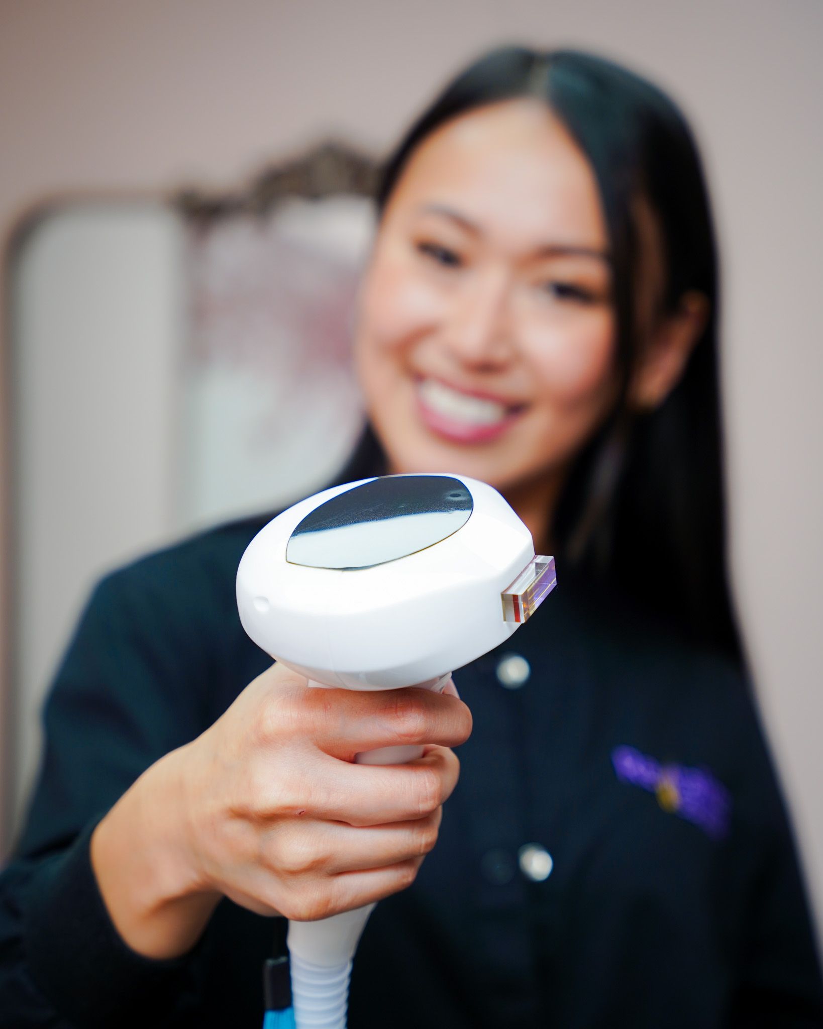 A woman is smiling while holding a white device in her hand