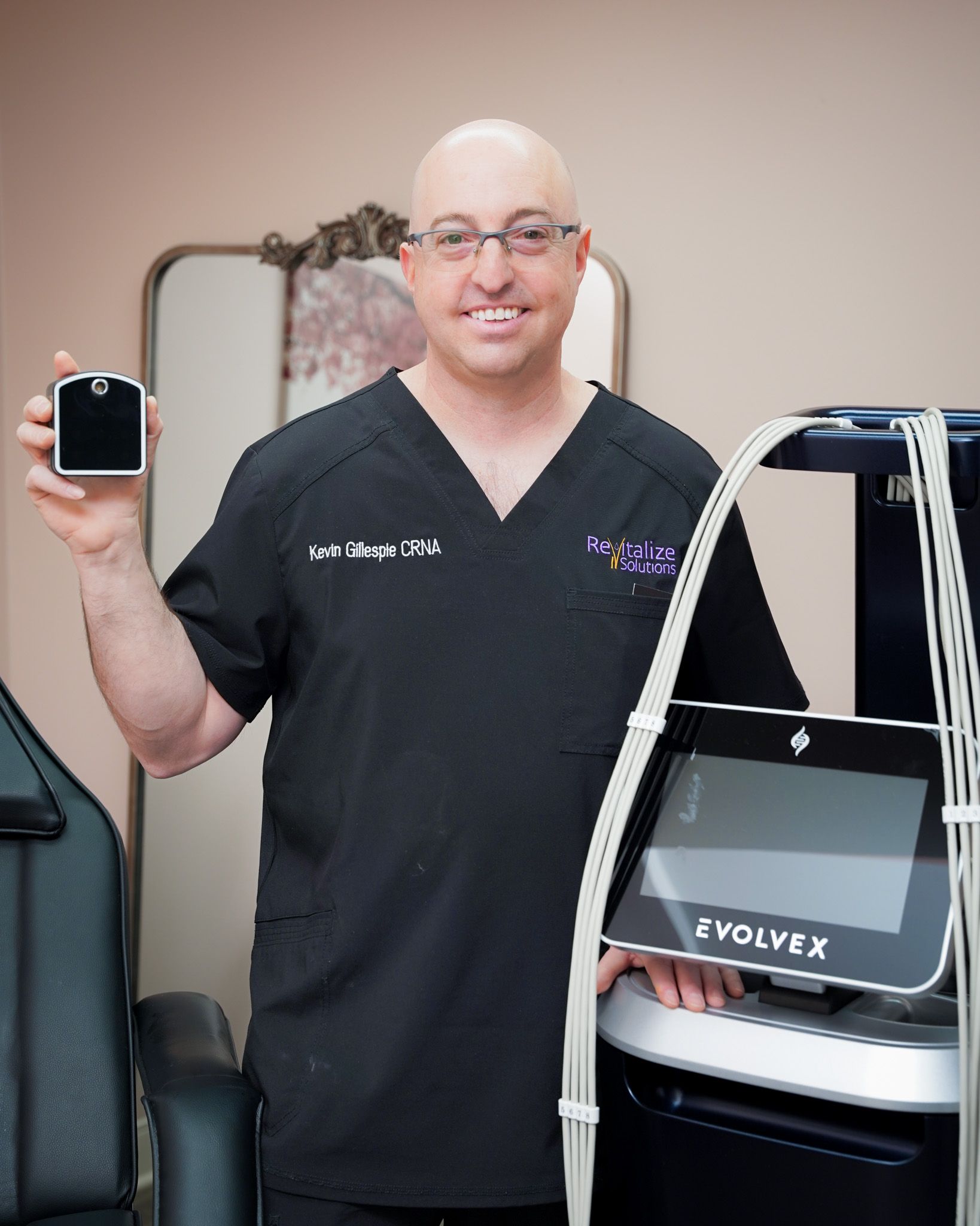 A man in a scrub top is holding a cell phone and a machine.