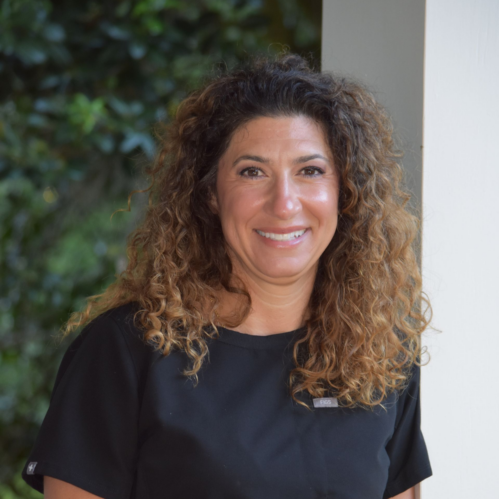 Smiling woman with curly dark hair against a light background