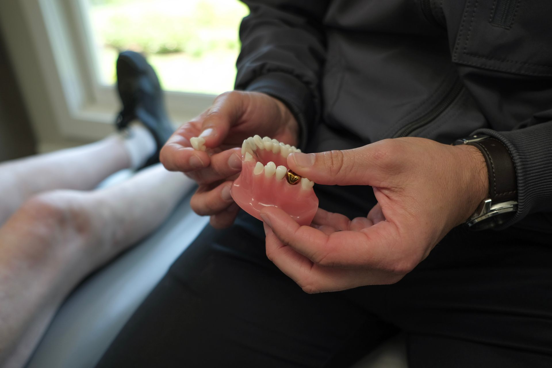 Gloved hands holding a dental mold while pointing at it in a clinic setting