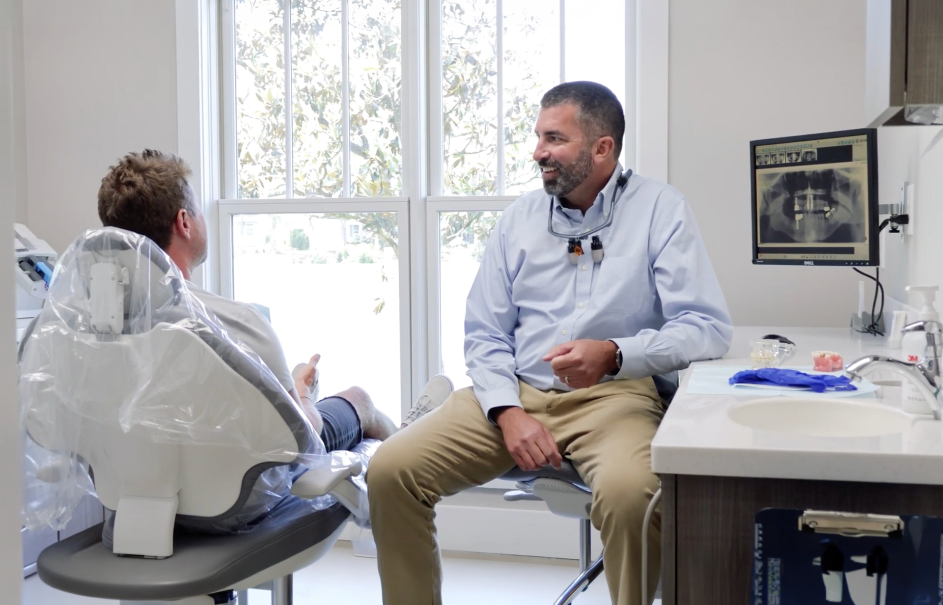 Patient reclining in a dental chair during a dental treatment, with equipment and tools nearby