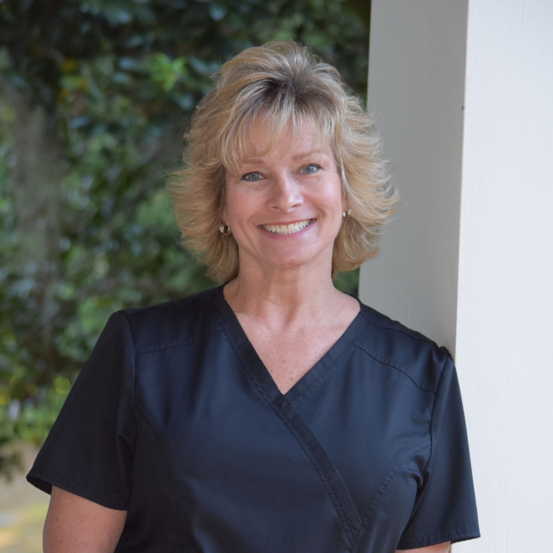 Smiling blonde woman with short hair against a plain light background