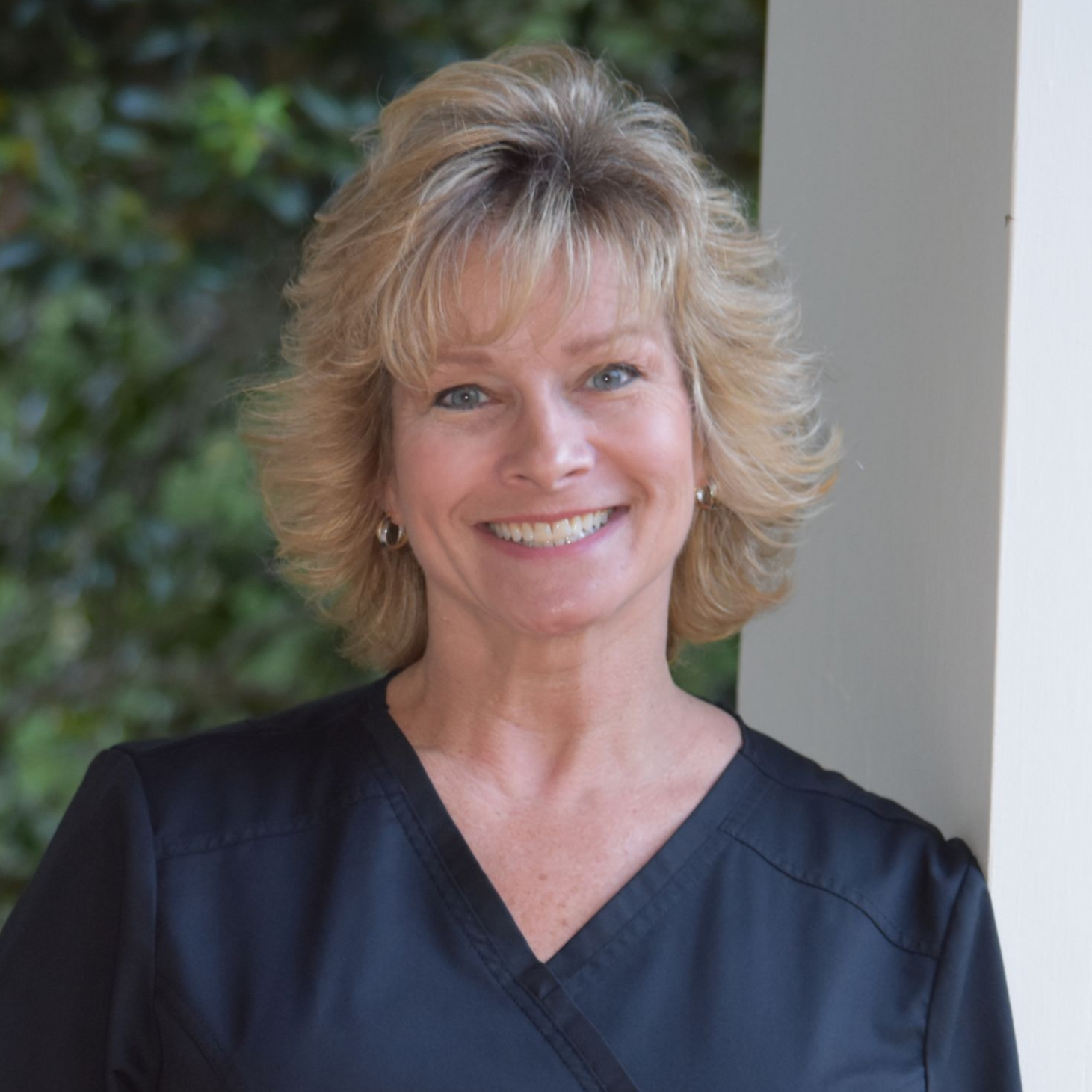 Smiling blonde woman with short hair against a plain light background