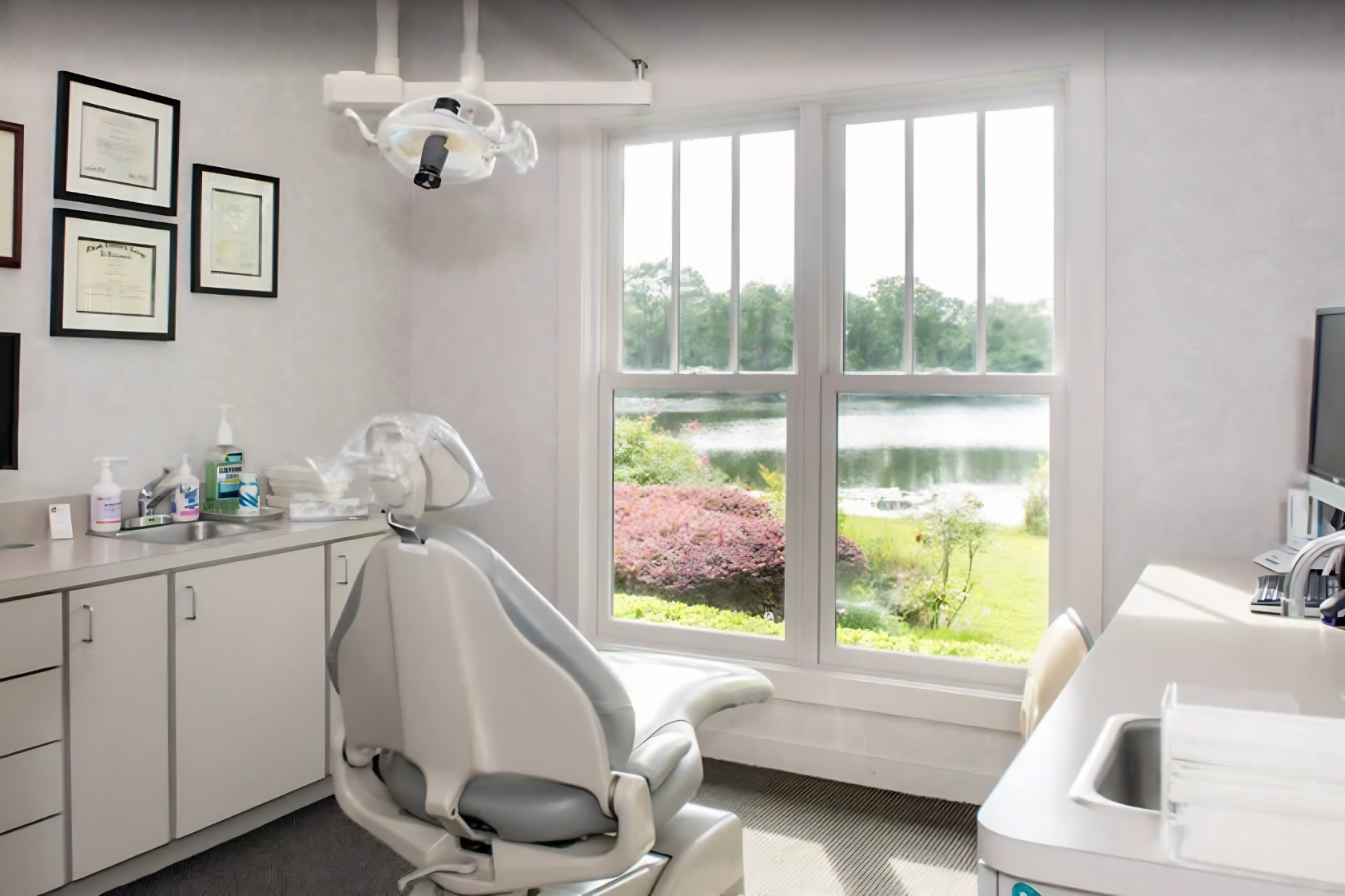 Bright dental exam room with chair, window view, and cabinets