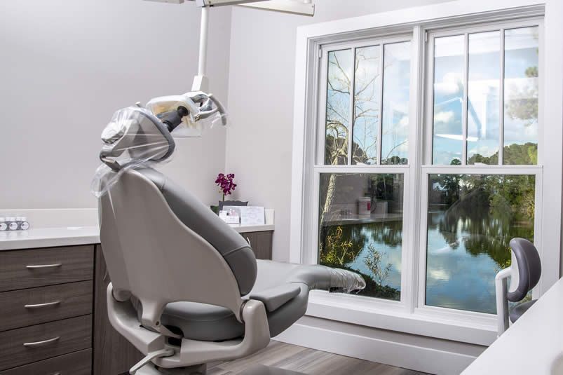 Dental exam room with reclining chair, overhead light, and large window