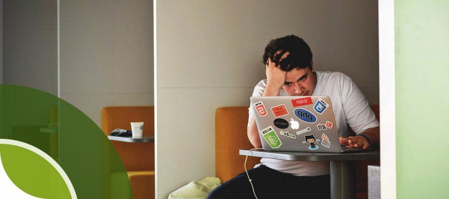 A man is sitting at a table using a laptop computer.