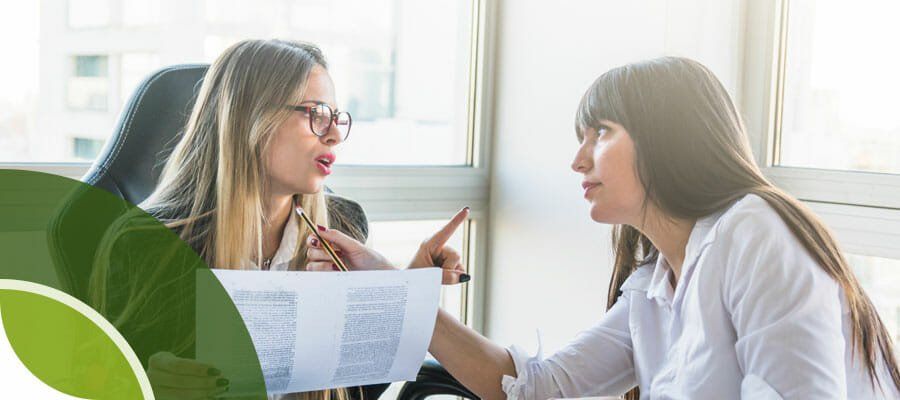 Two women are sitting at a table talking to each other.