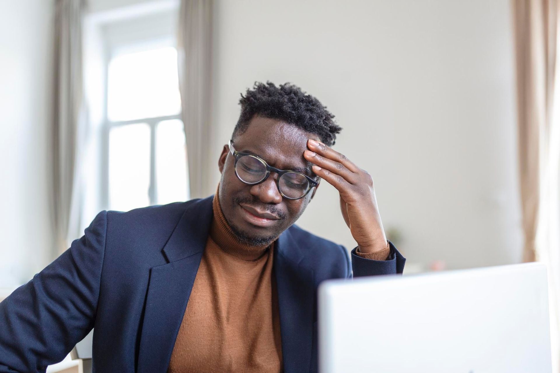 A man in a suit and glasses is sitting in front of a laptop computer.