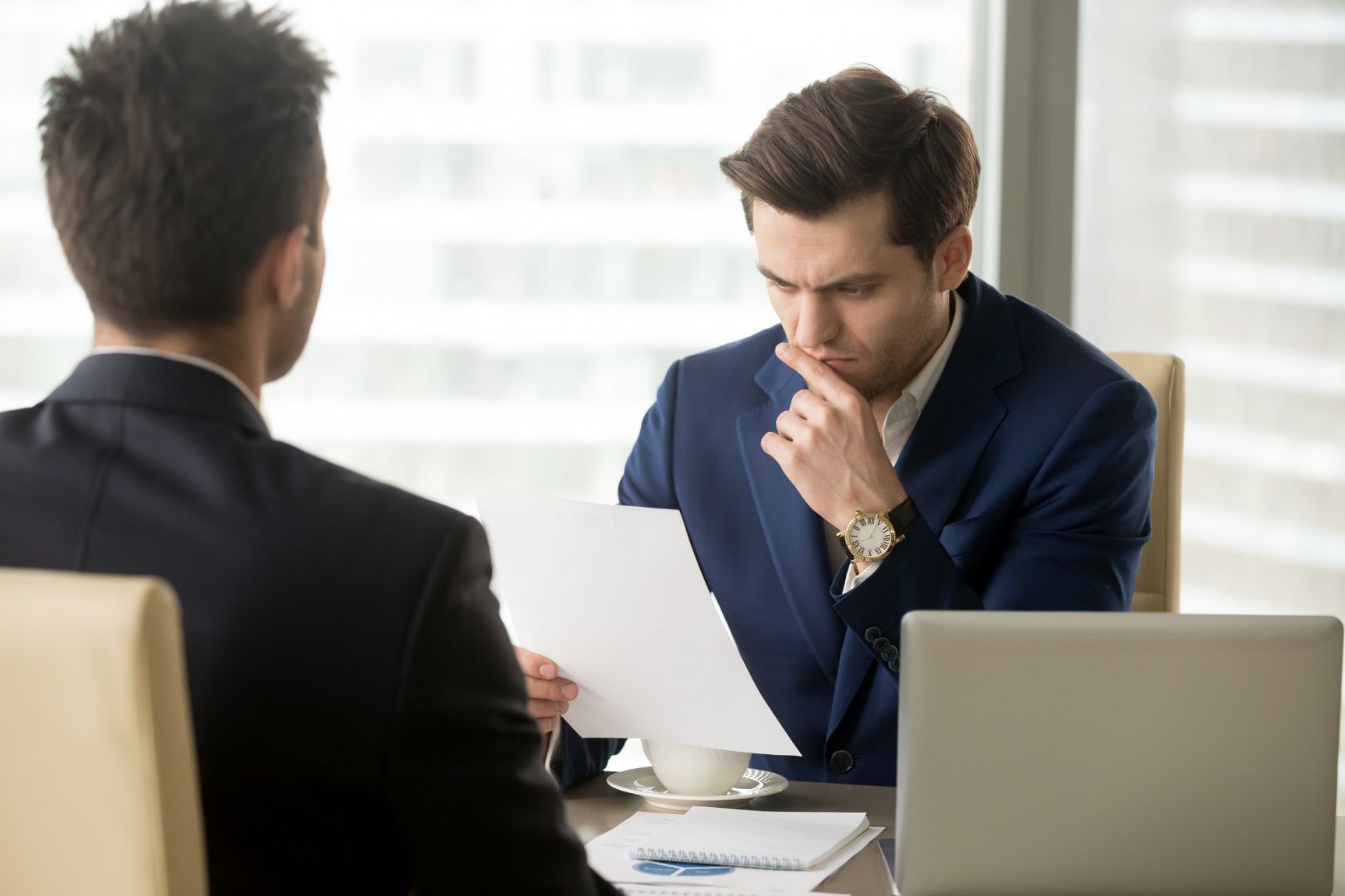 Two men are sitting at a table looking at a piece of paper.