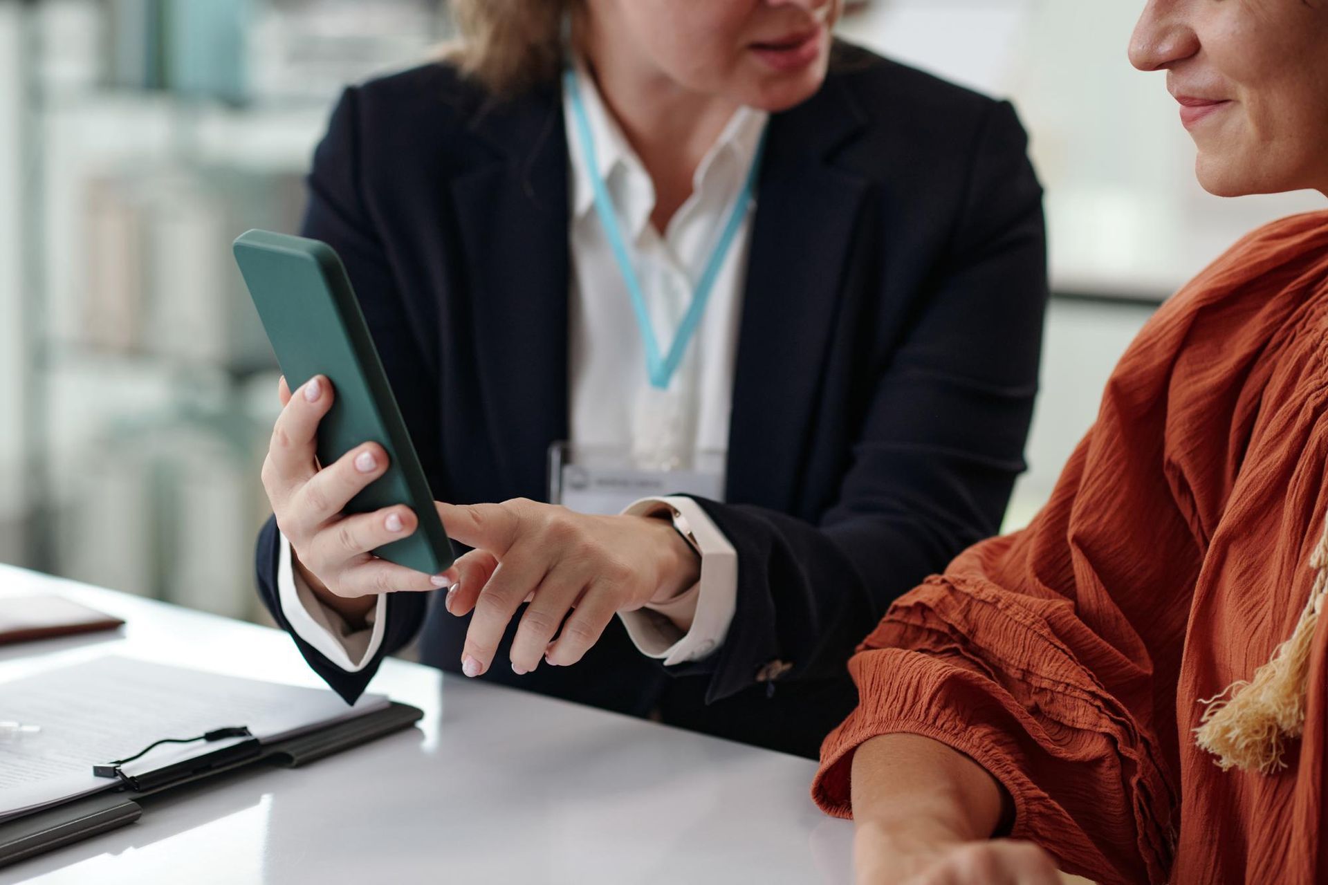Two people discussing a tablet at a desk, one pointing at the screen in an office setting.